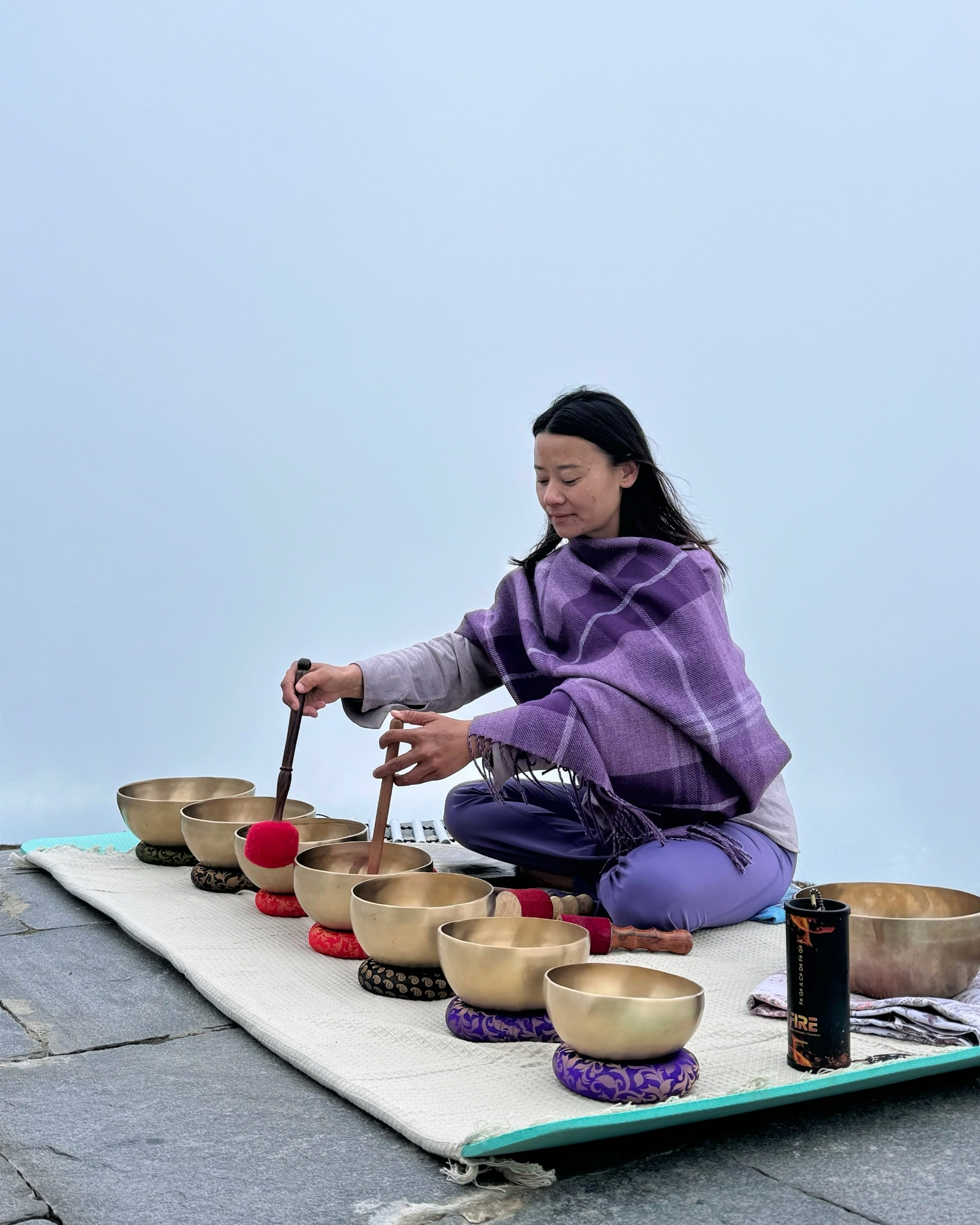 Sound bath in the mist Yangchen playing singing bowls during an outdoor sound bath session in Bhutan